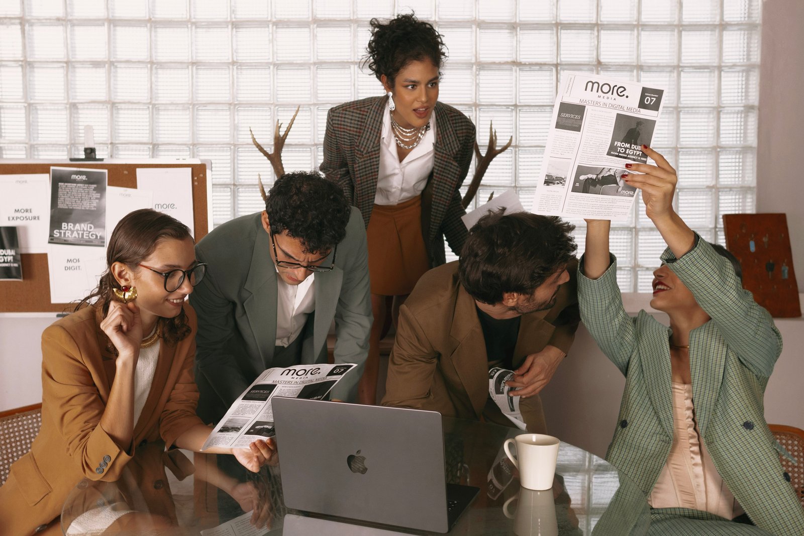 Media agency team brainstorming digital marketing strategies around a laptop in a modern office