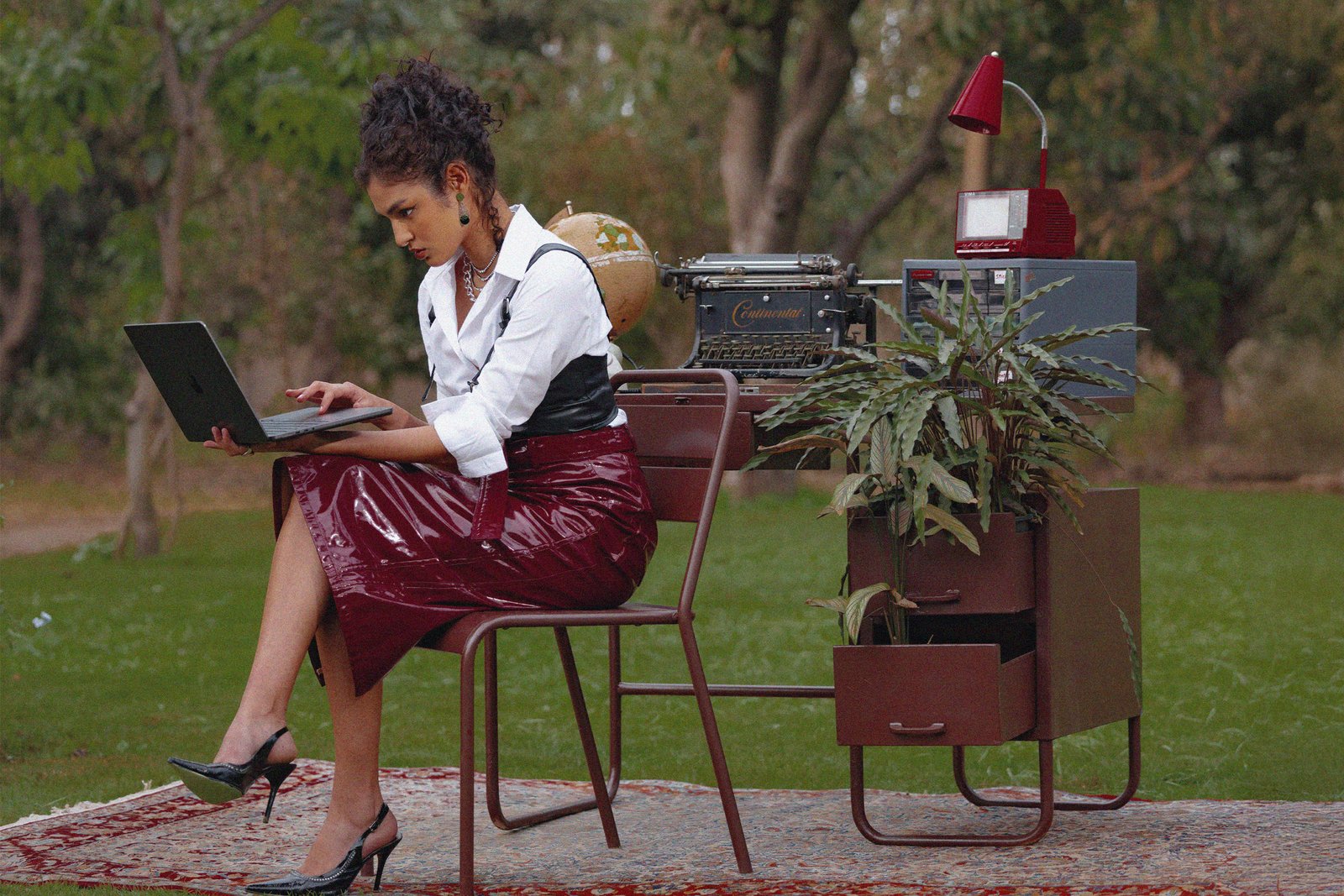 Creative media strategist working remotely in garden with laptop, typewriter, and vintage decor